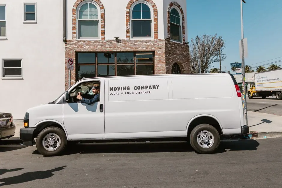 White moving company van parked on city street on a sunny day, showcasing local and long distance services.